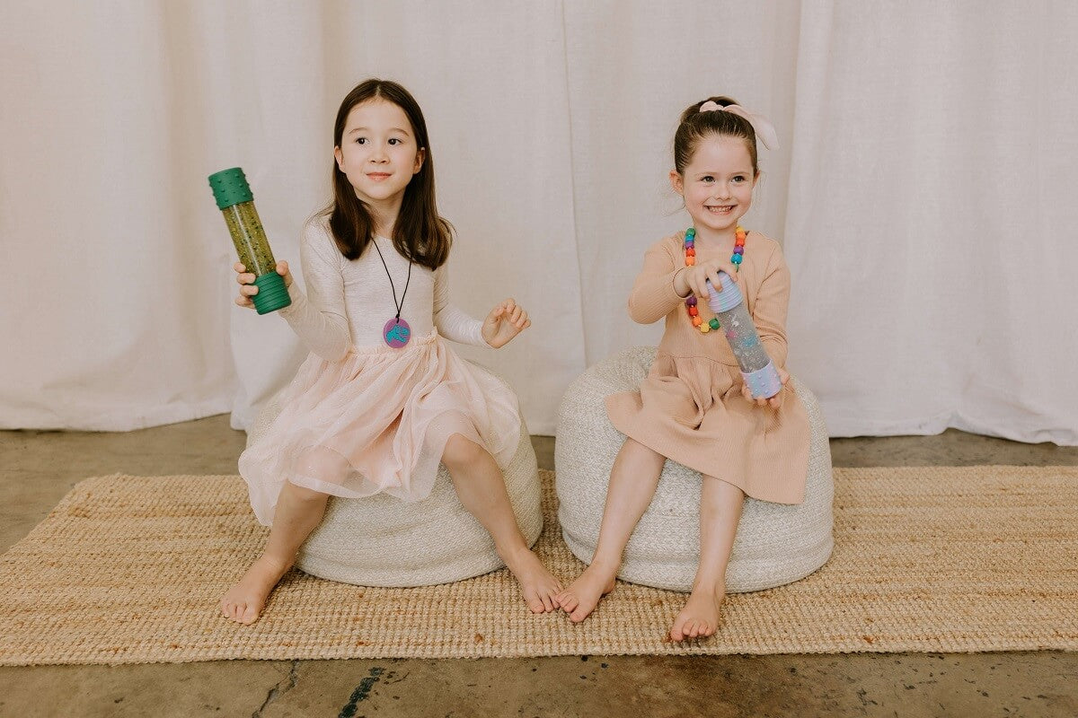 Two children playing with A colorful sensory bottle filled with shimmering glitter and captivating elements, designed to engage and stimulate children's senses and promote relaxation.