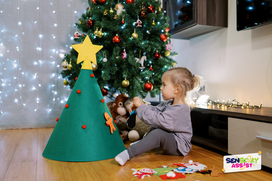  Little girl hangs a sensory toys on a toy Christmas tree while sitting on the floor of the room.