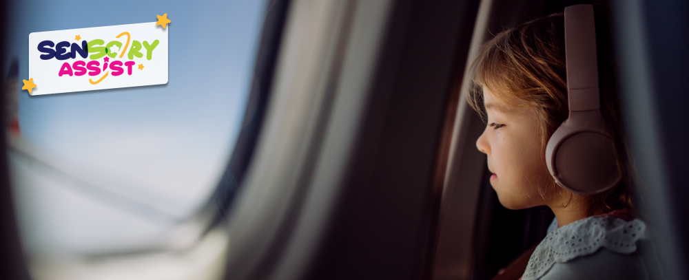 Little girl whit ear muff in airplane looking out of the window.