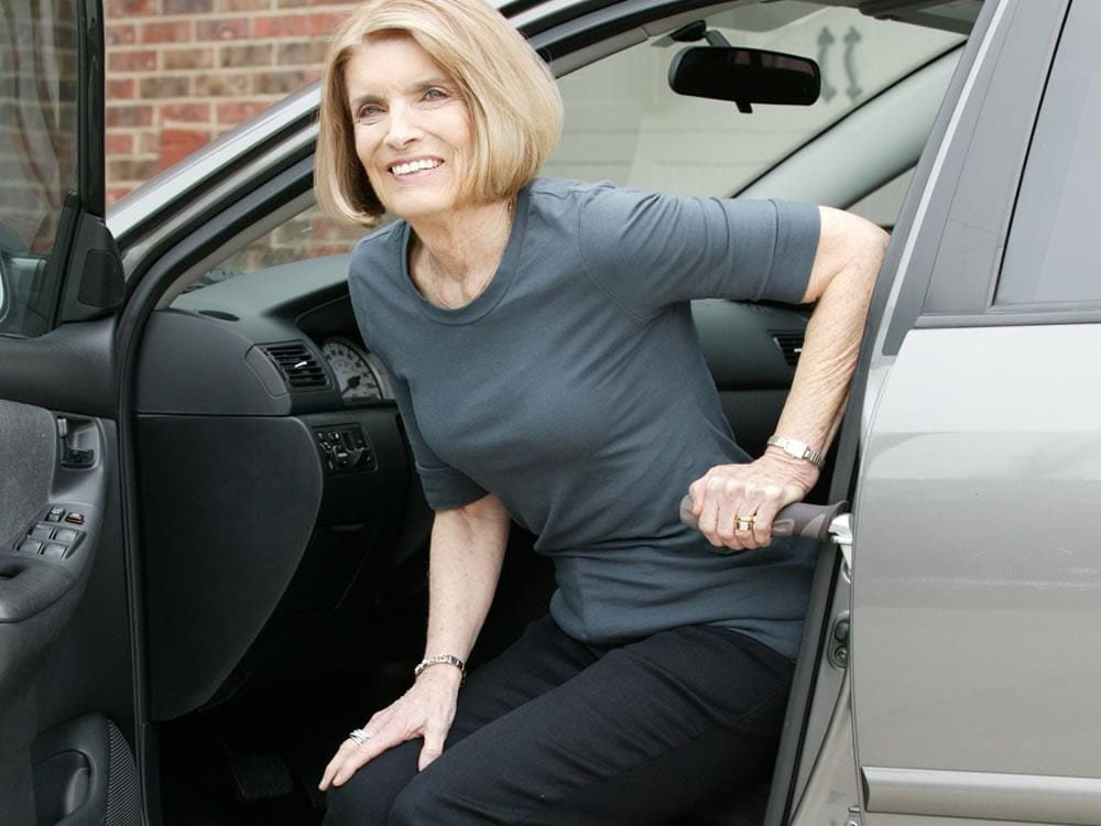 Woman using the Metro Car Handle Plus to get out of a car