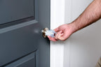 Hand turning a grip-fitted door knob on a grey door