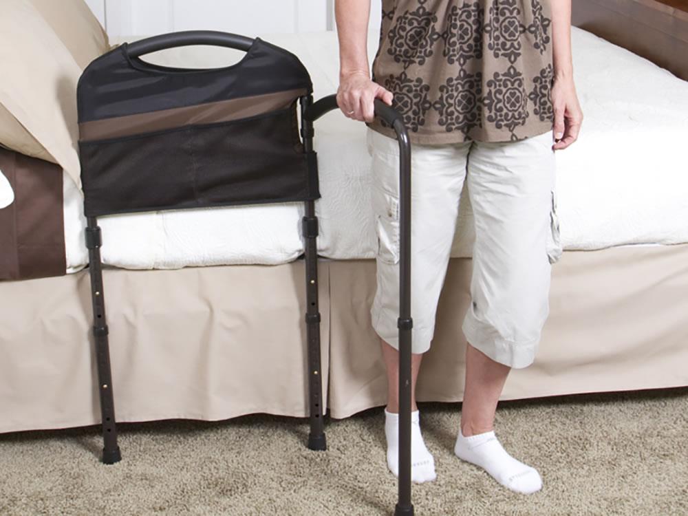 Man standing beside the bed holding the Mobility Bed Rail