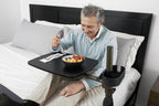 Man using a laptop on the Freedom Overbed Table in bed