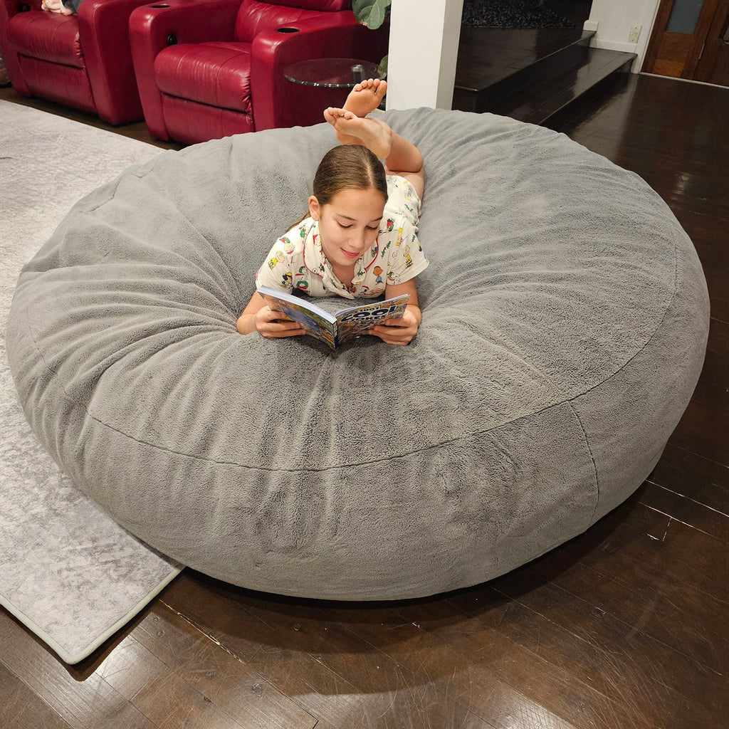 Child reading on a Steel Grey Sensory Pod foam beanbag indoors